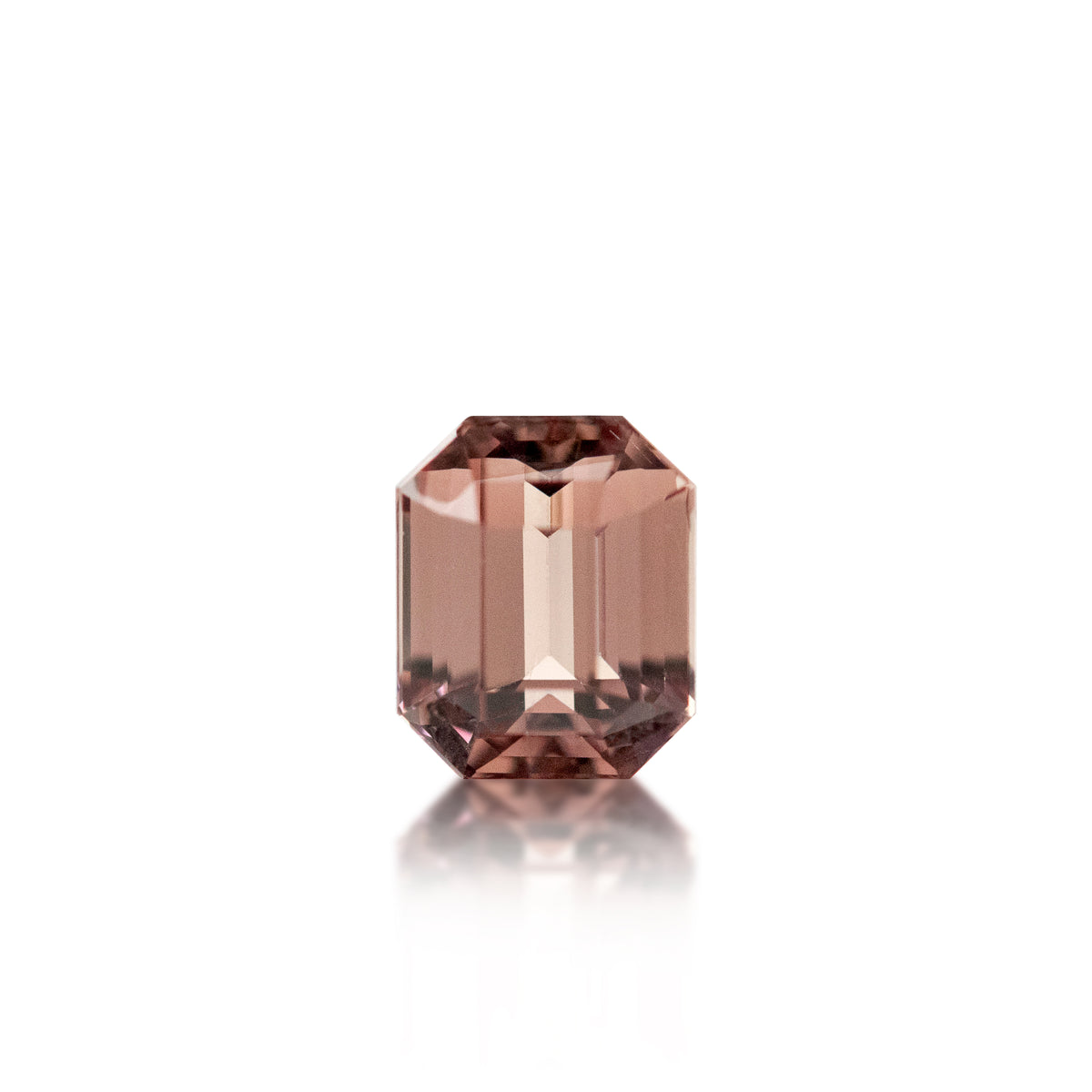 A single faceted rectangular gemstone with a dusty rose or mauve-pink color, centered on a clean white background with a soft reflection below.