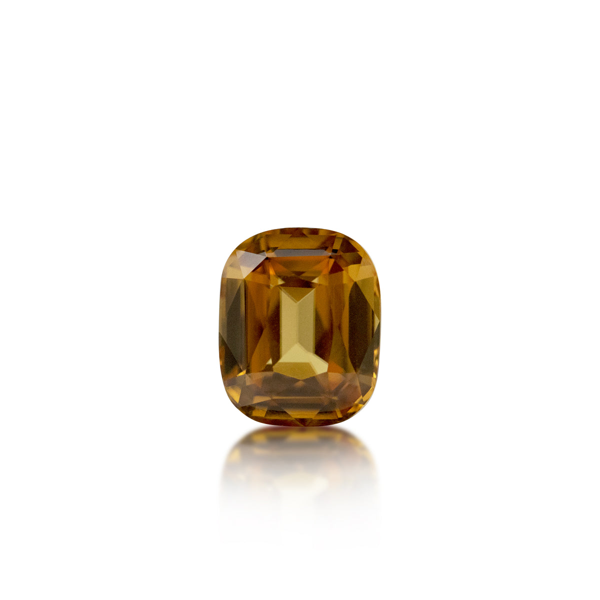 A cushion-cut yellow gemstone with a faceted, geometric design, displayed on a clean white background with a soft reflection below.