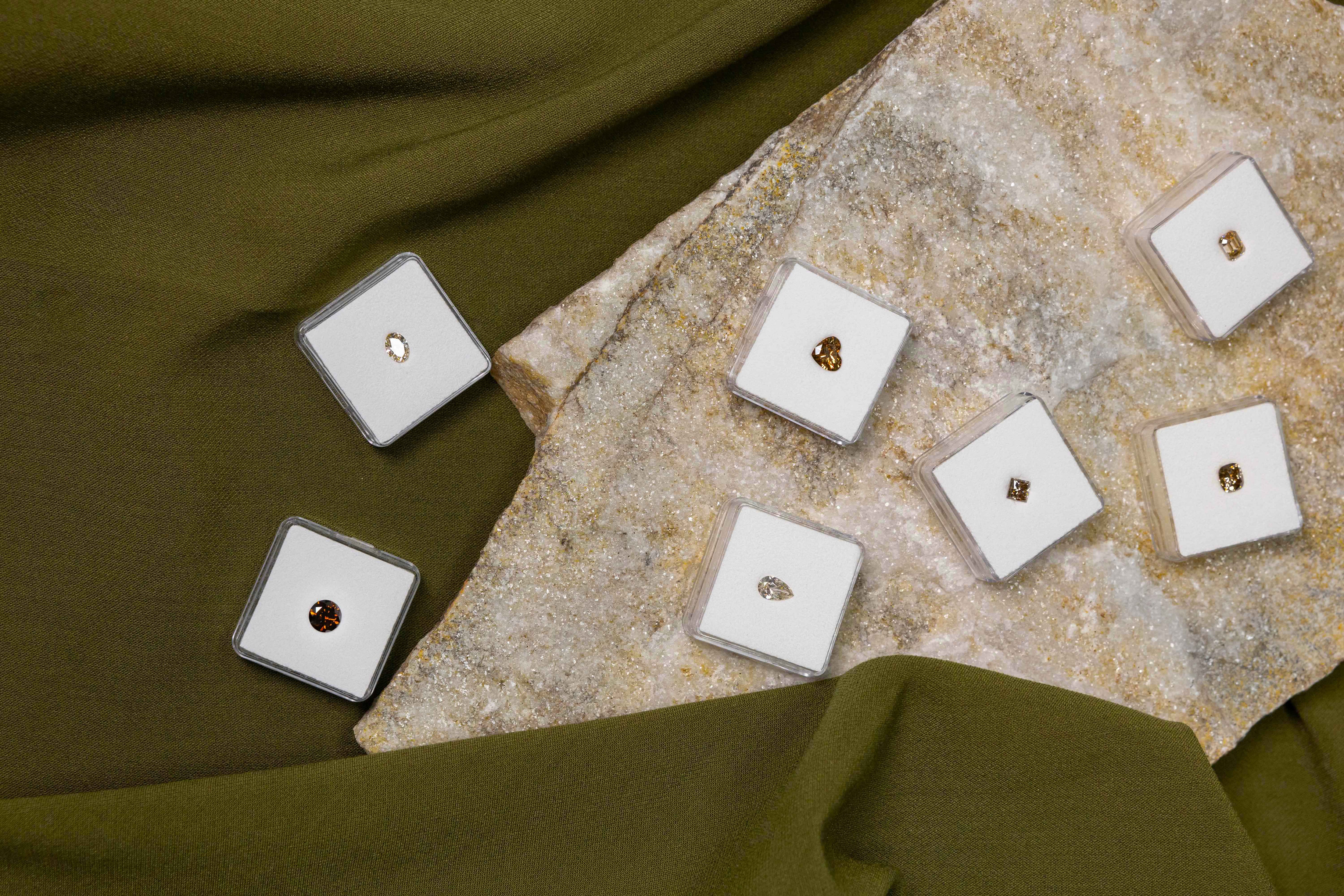 Jewelry boxes with heart-shaped, square and round gemstones on a stone surface.