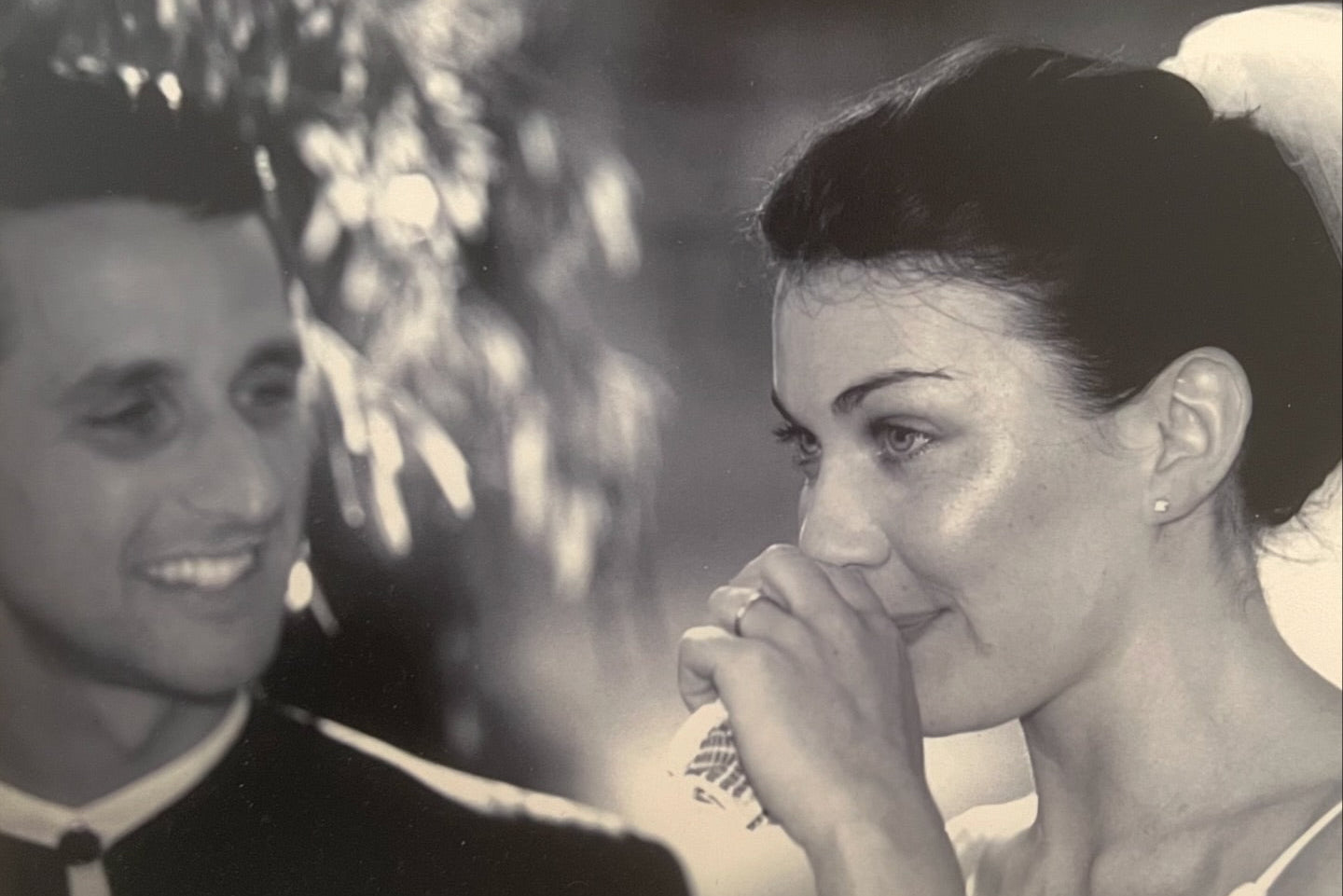 Black and white photo of a couple, bride and groom, with a blurred background. Bride wearing diamond earrings.