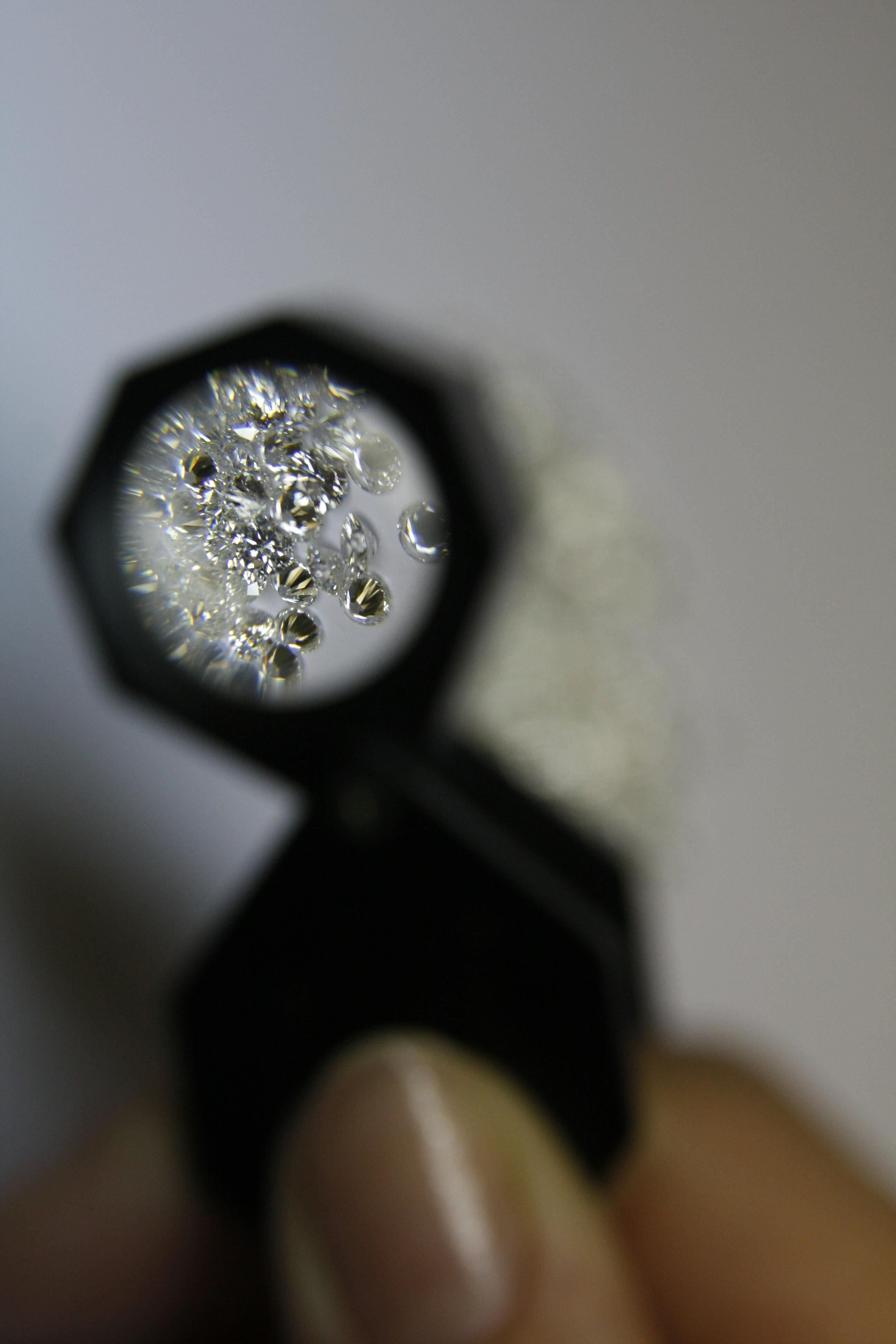Close-up of a diamond held under a magnifying glass with a blurred background