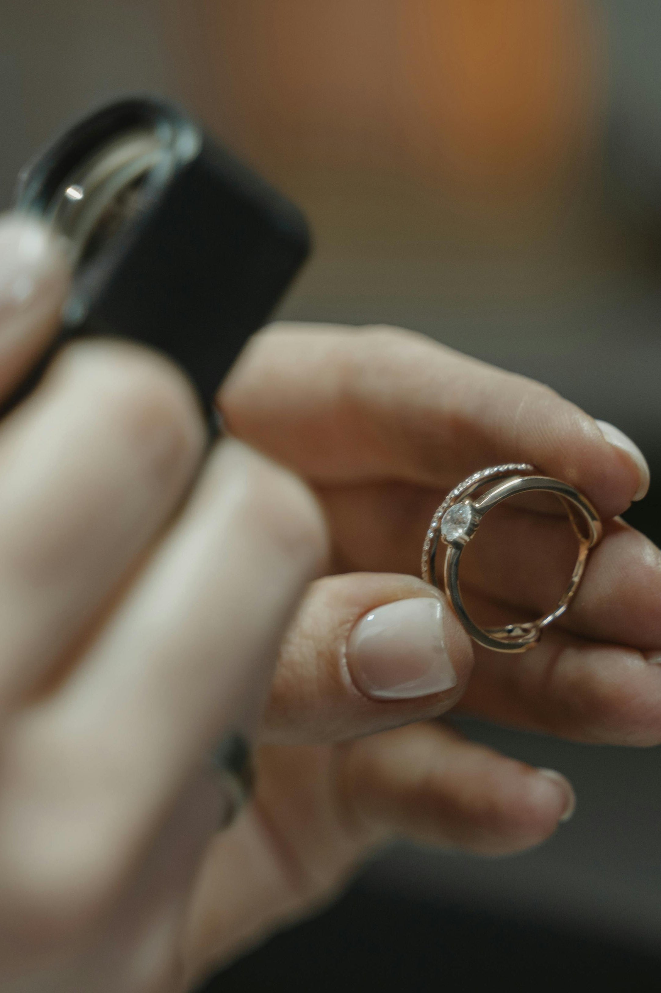 Close-up of hands holding a ring against a blurred background, microscope, diamonds