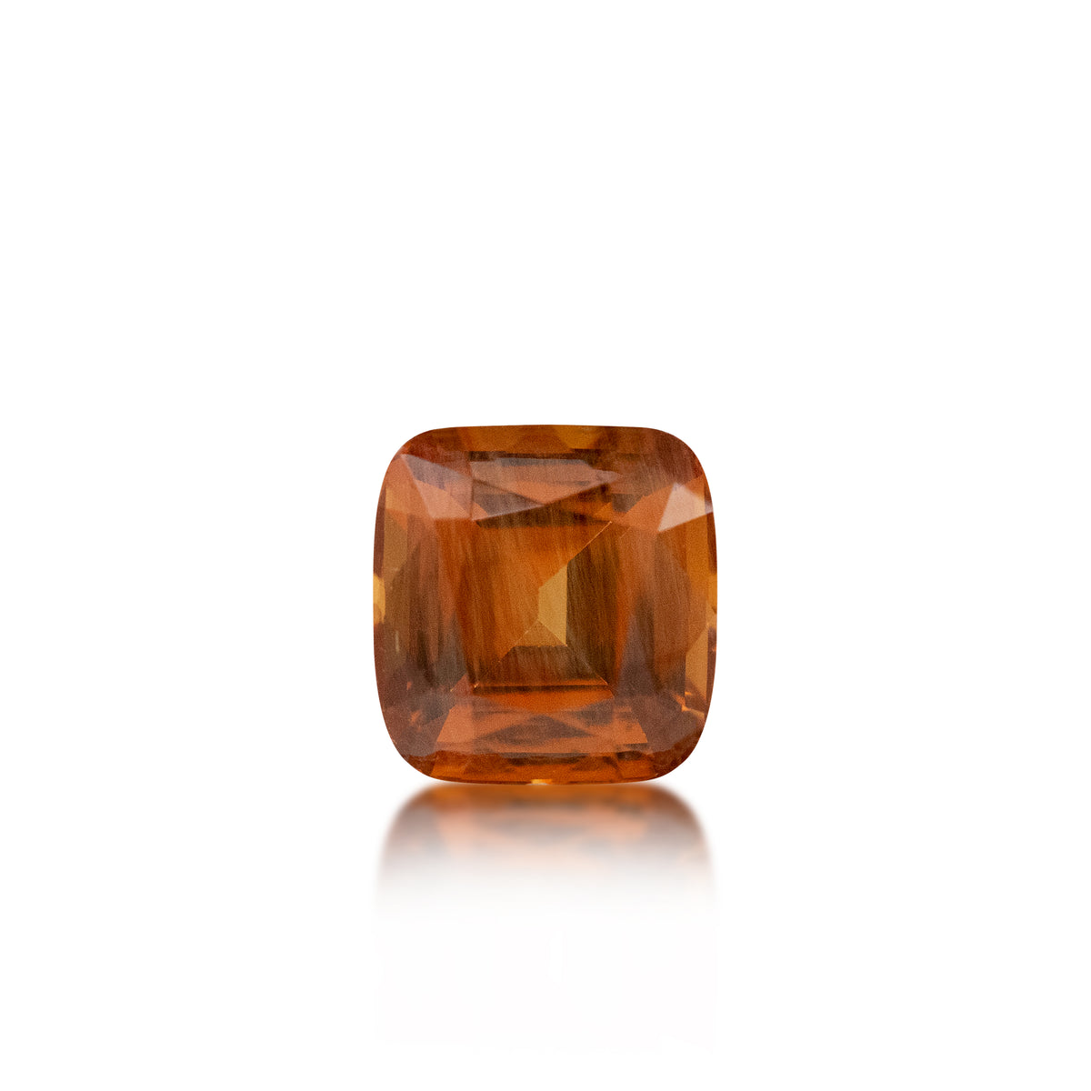 A cushion-cut orange gemstone with a faceted, geometric pattern, centered on a solid white background with a soft reflection below.