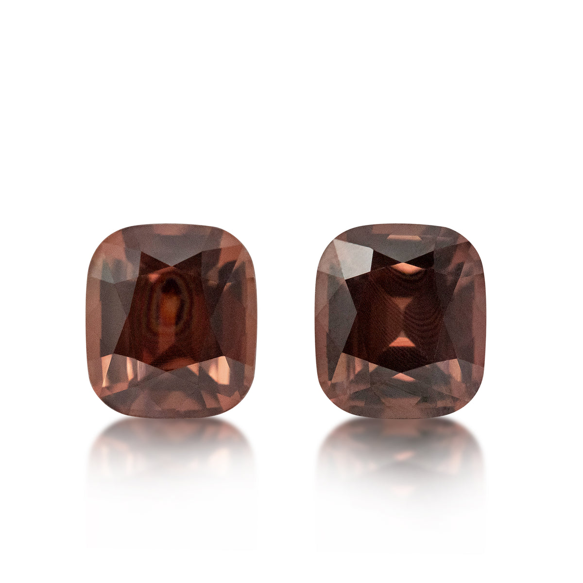 A pair of cushion-cut gemstone stud earrings in a warm reddish-brown hue, displayed on a clean white background with soft reflections below.