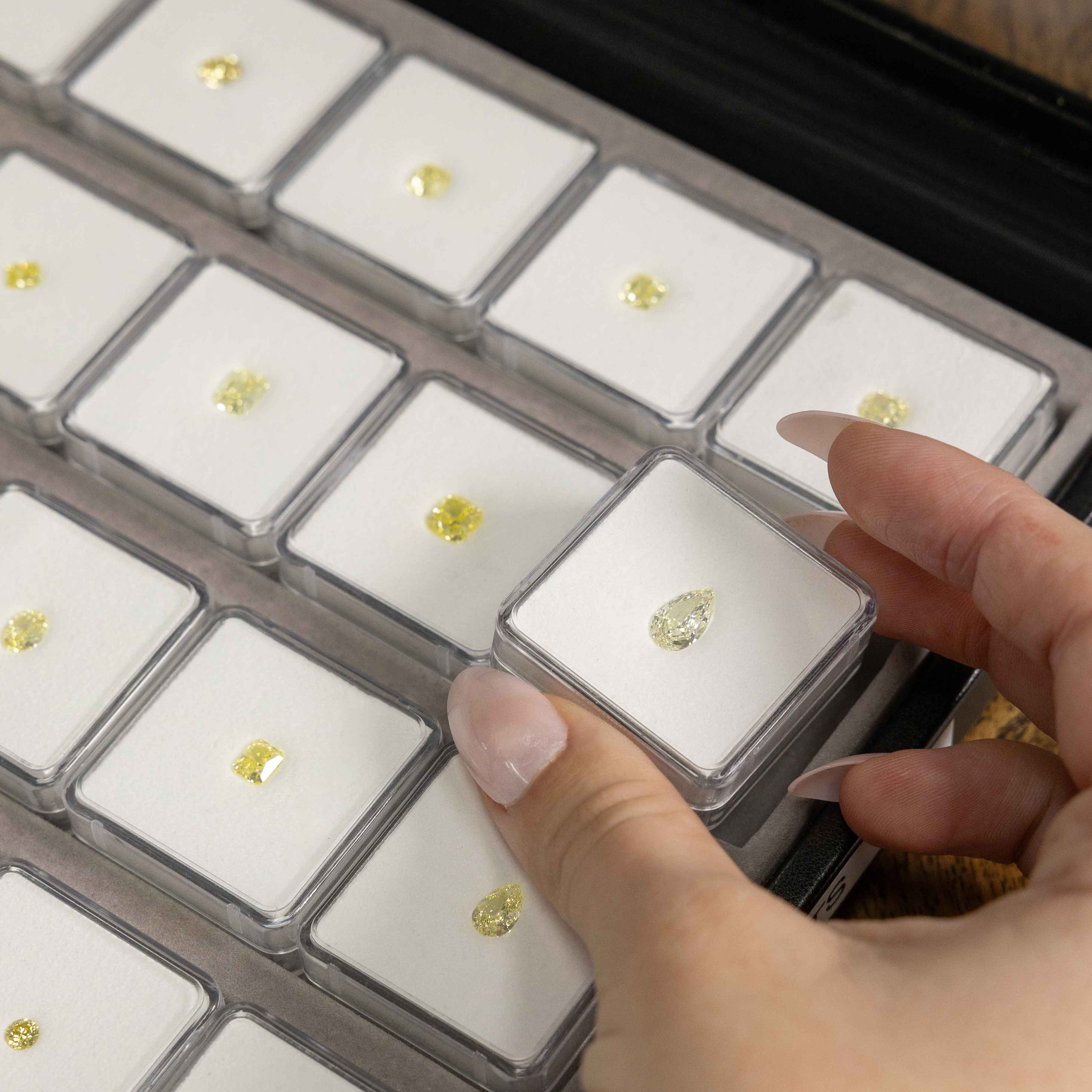Hand holding a diamond in a clear case with other diamonds