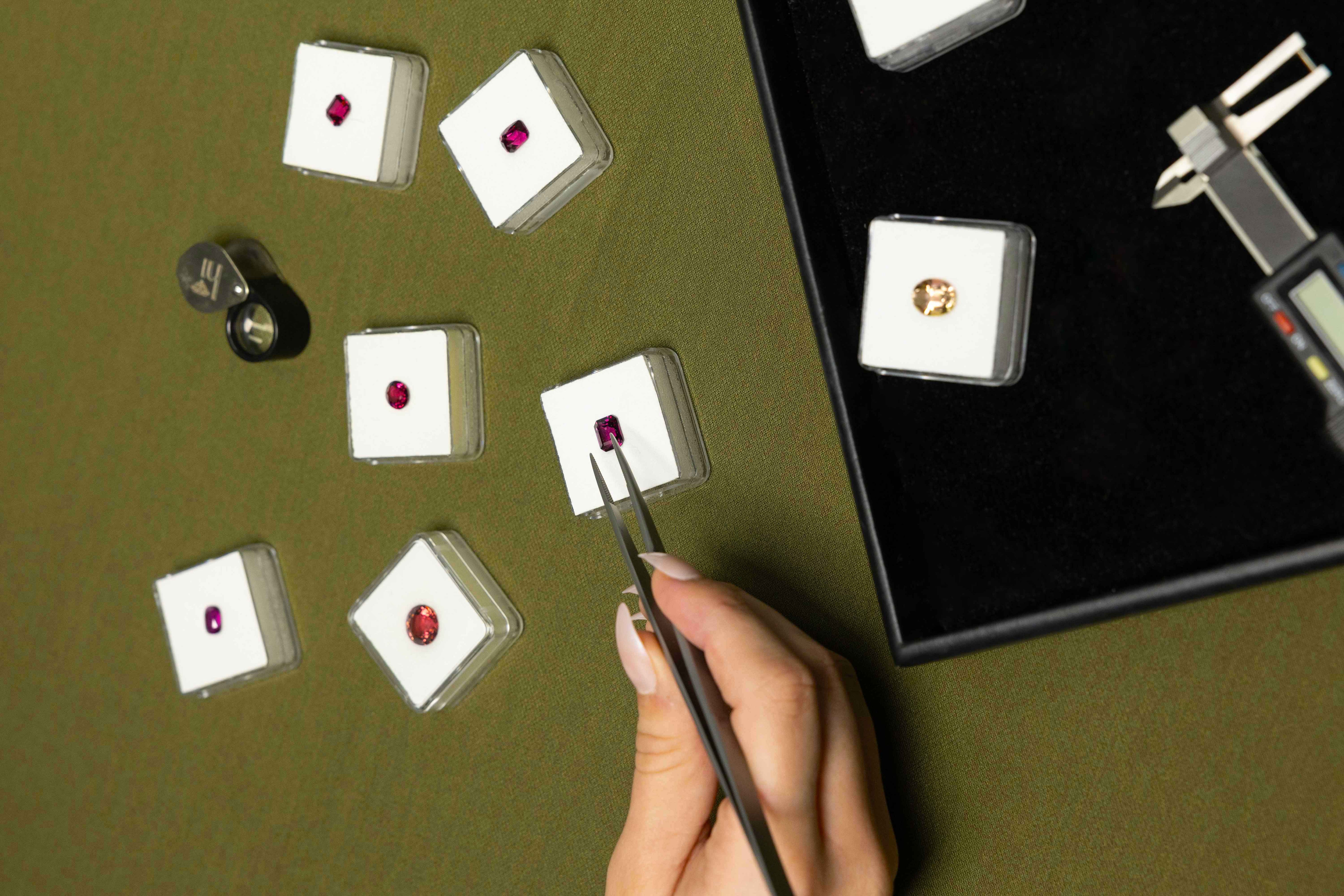 Person examining small diamonds on display cards with a magnifying tool.